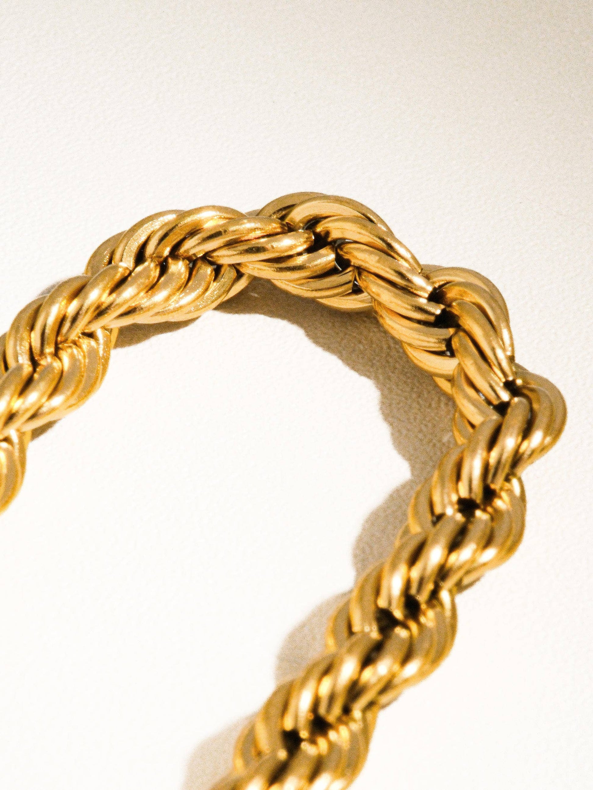 a close up of a gold chain on a white surface