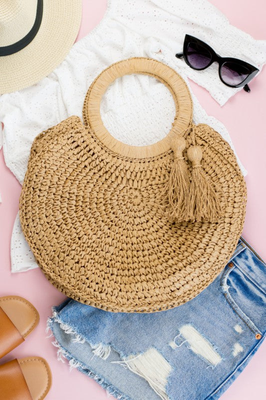 a straw bag, sunglasses and a pair of jeans on a pink background