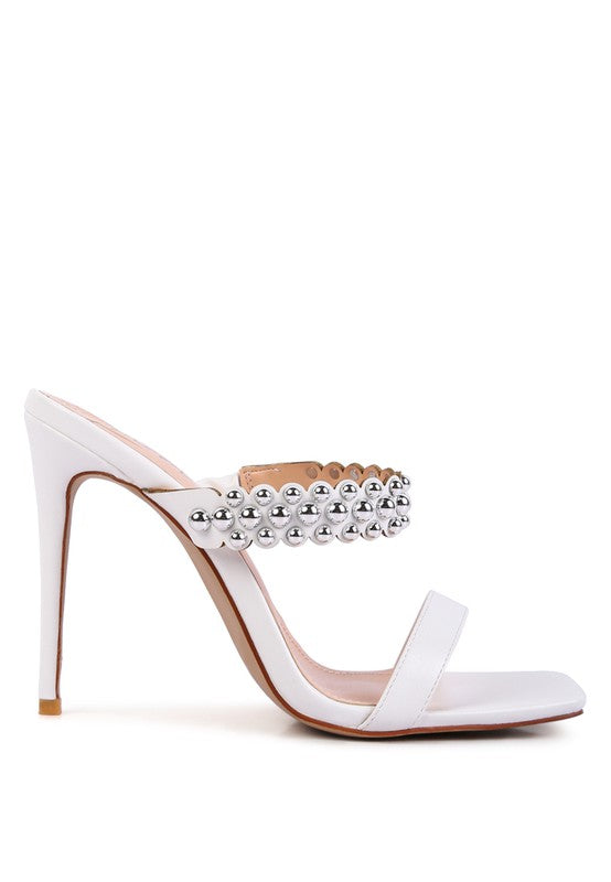 a white high heeled sandal with a crystal embellishment