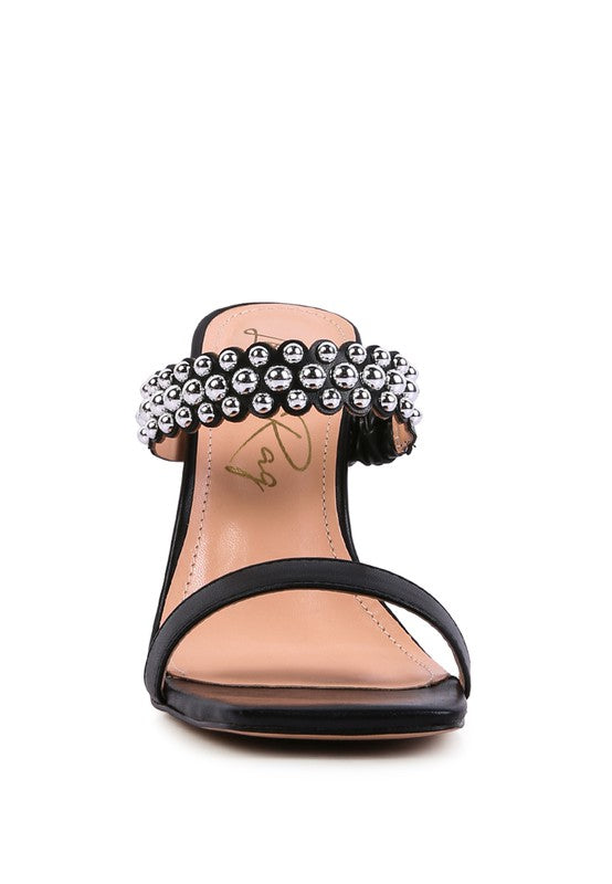 a woman's black sandals with pearls on the toes