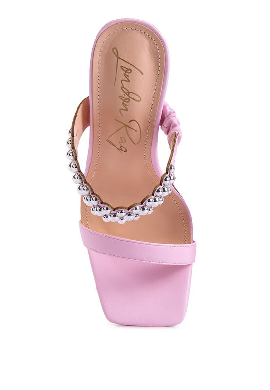 a pink high heeled sandal with a beaded strap