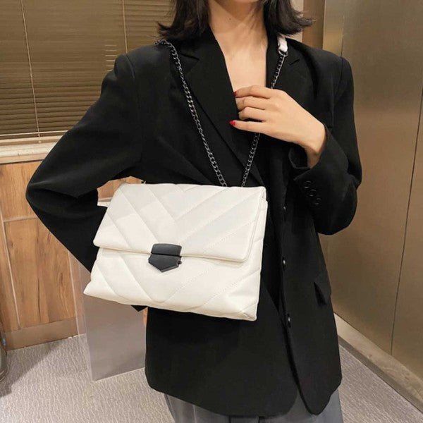 a woman wearing a black blazer holding a white purse