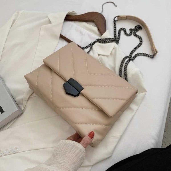 a woman's hand is holding a beige purse