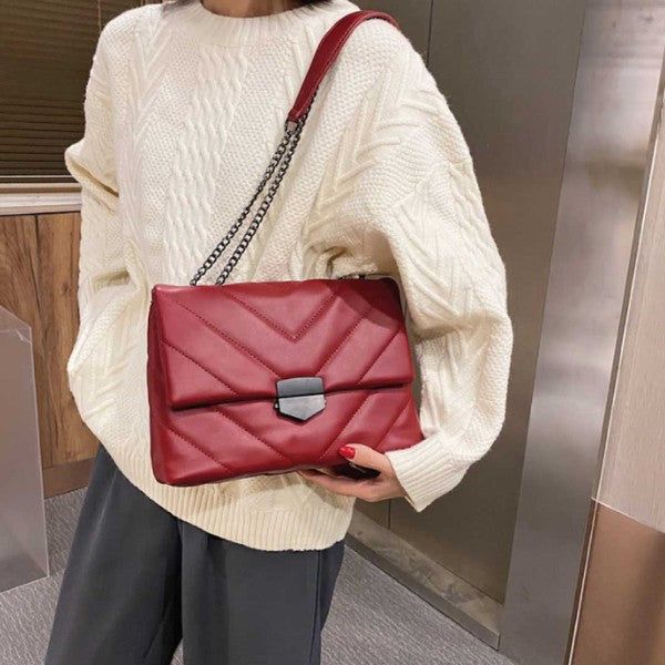 a woman in a white sweater holding a red purse