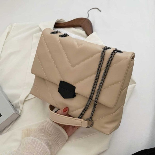 a woman holding a beige handbag on top of a bed