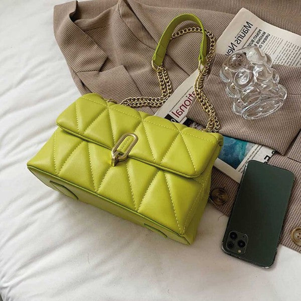 a green purse sitting on top of a bed next to a cell phone