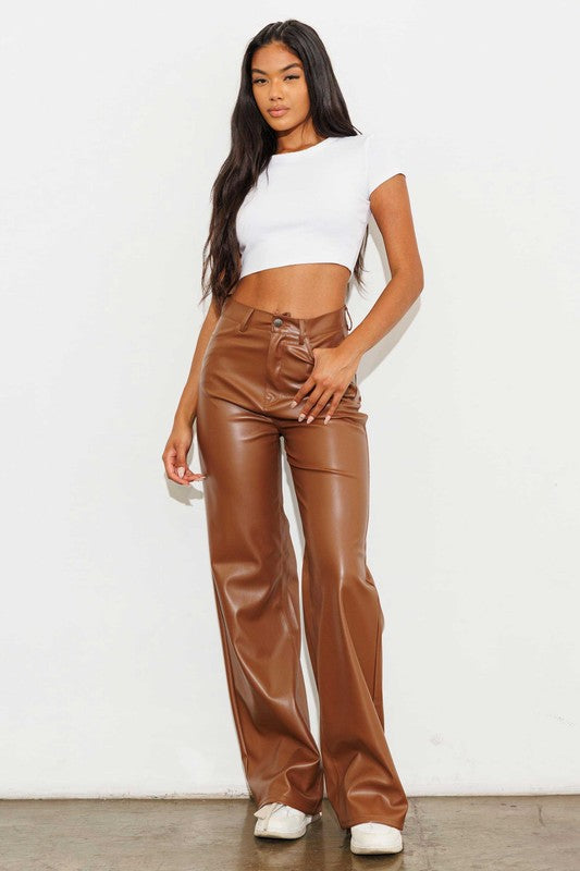 a woman wearing brown leather pants and a white top