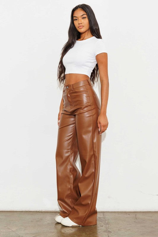 a woman in a white top and brown leather pants