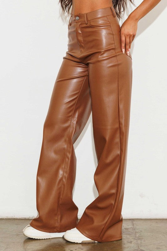 a woman wearing brown leather pants and white sneakers