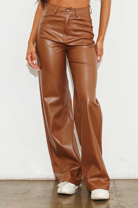 a woman wearing brown leather pants and a crop top