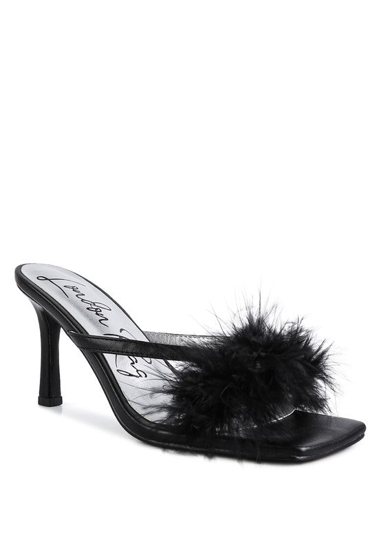 a pair of black shoes with a fur ball on the heel