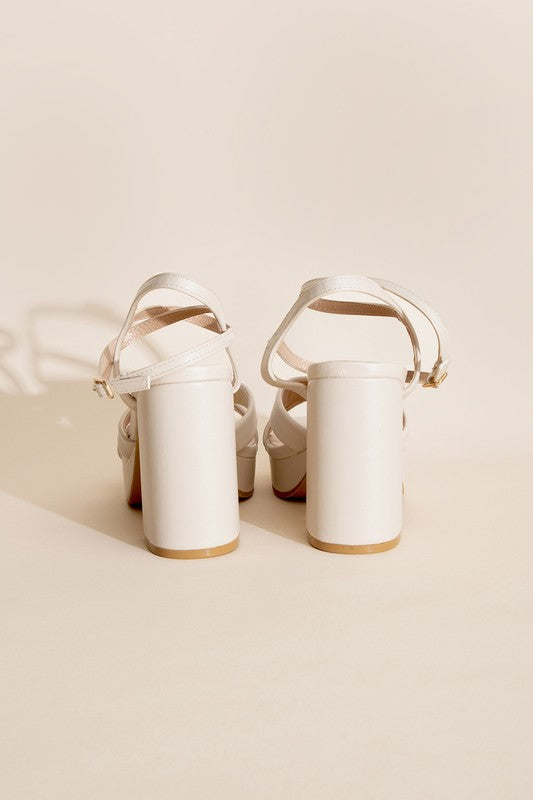 a pair of white high heeled shoes sitting on top of a table