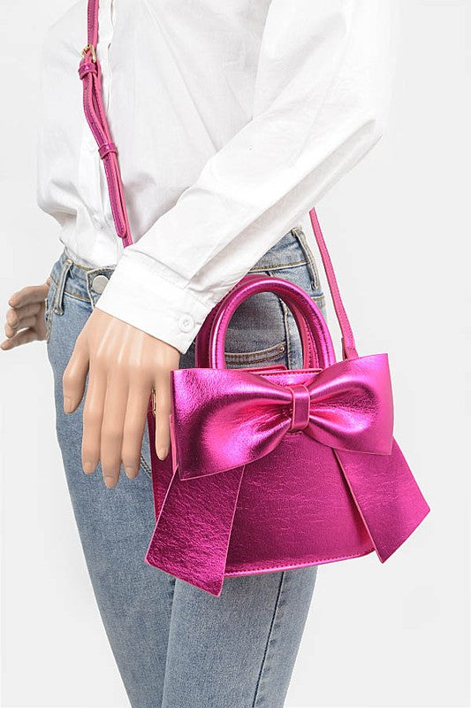 a woman holding a pink purse with a bow on it