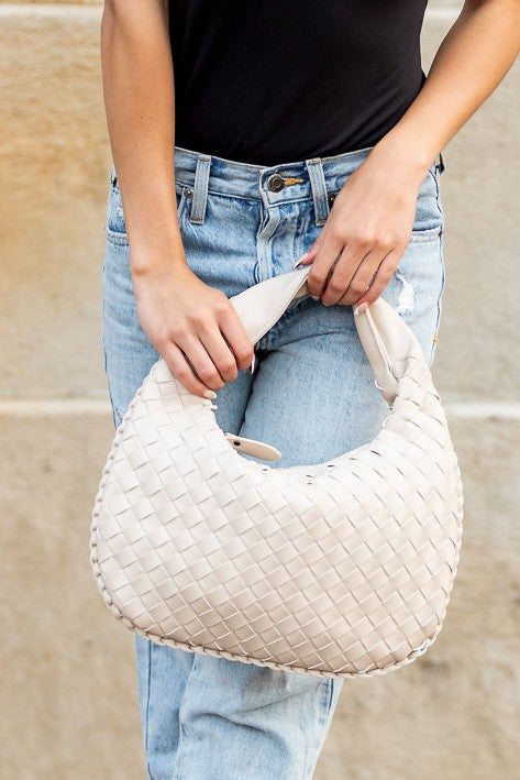 a woman holding a white purse in her hands