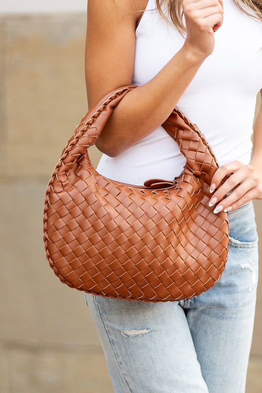 a woman holding a brown woven purse