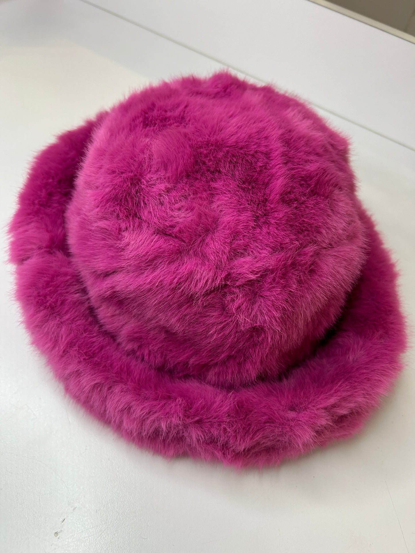 a pink hat is sitting on a white surface