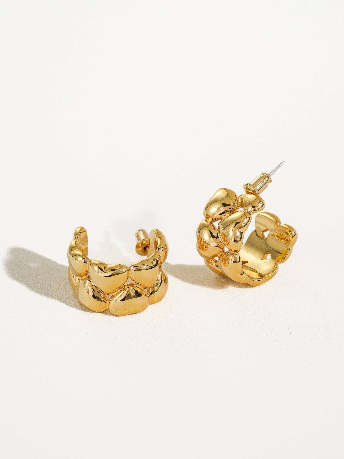 a pair of gold earrings on a white background