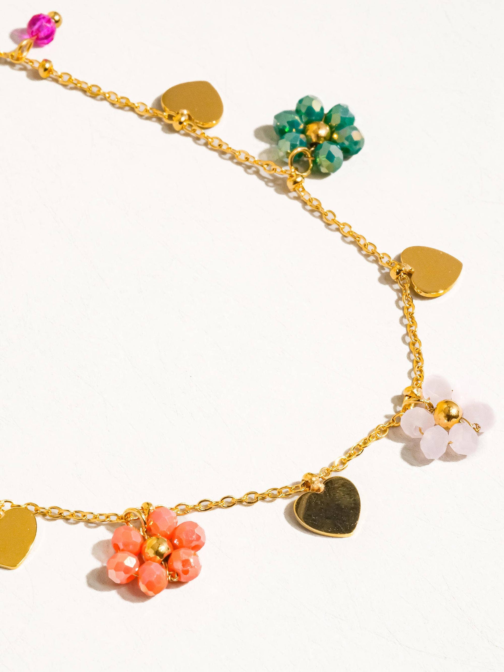 a gold chain bracelet with hearts and flowers