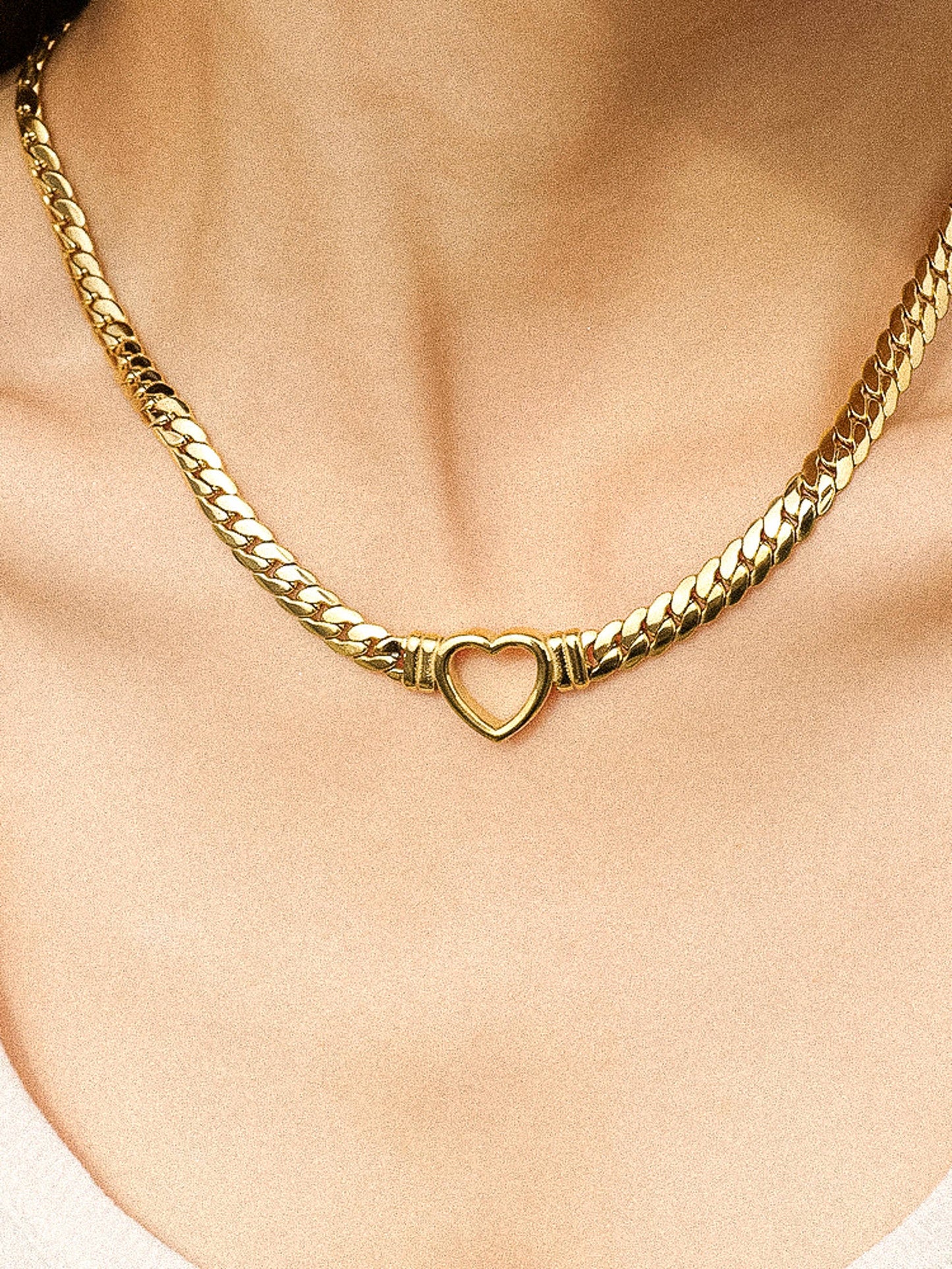 a woman wearing a gold necklace with a heart on it