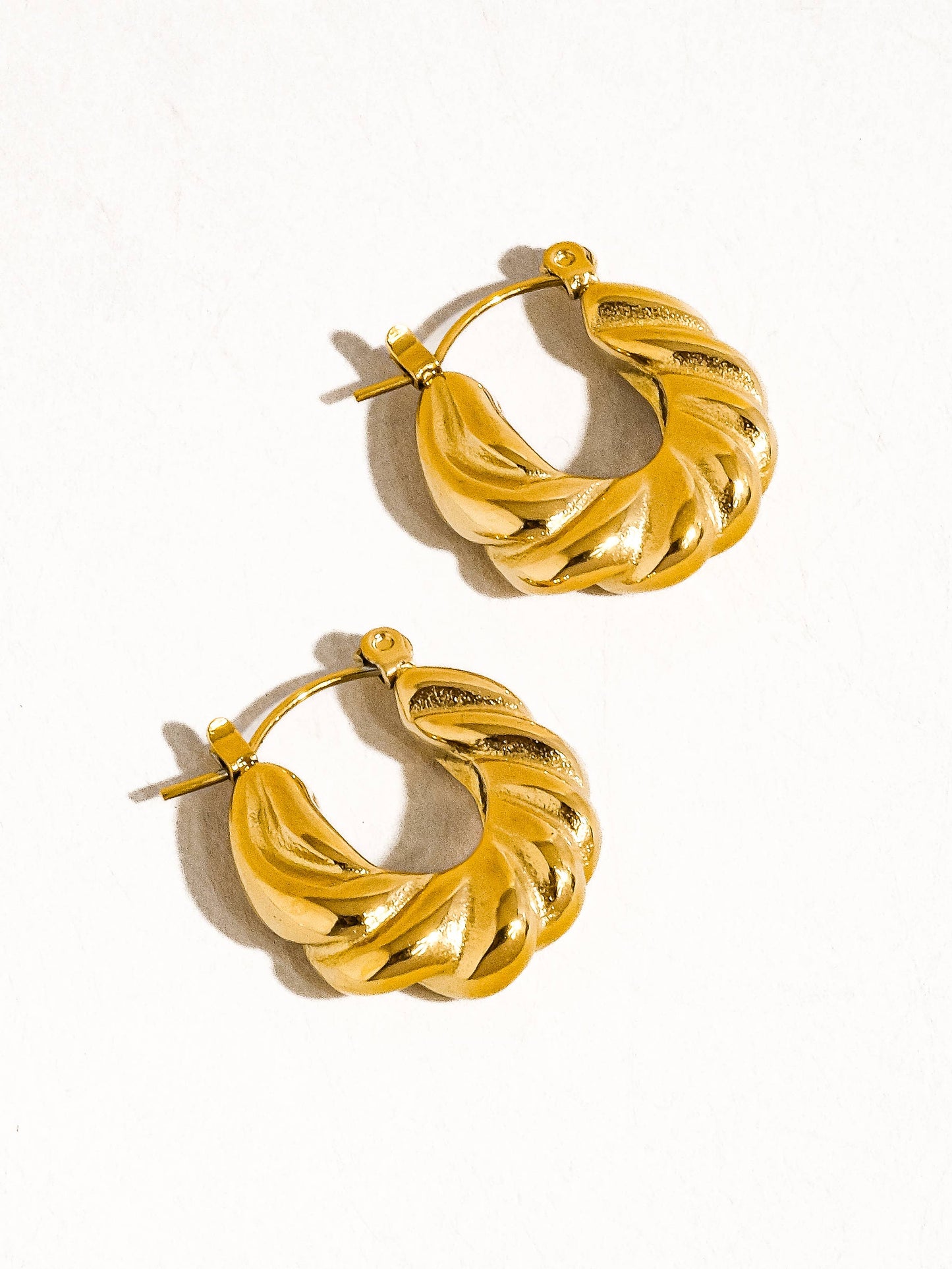 a pair of gold hoop earrings on a white background