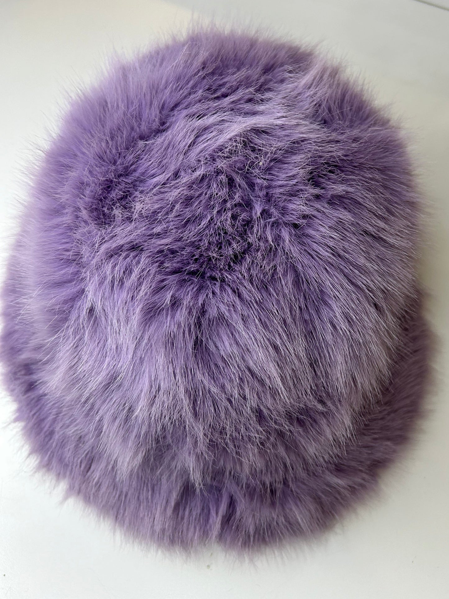 a purple fur ball sitting on top of a white table