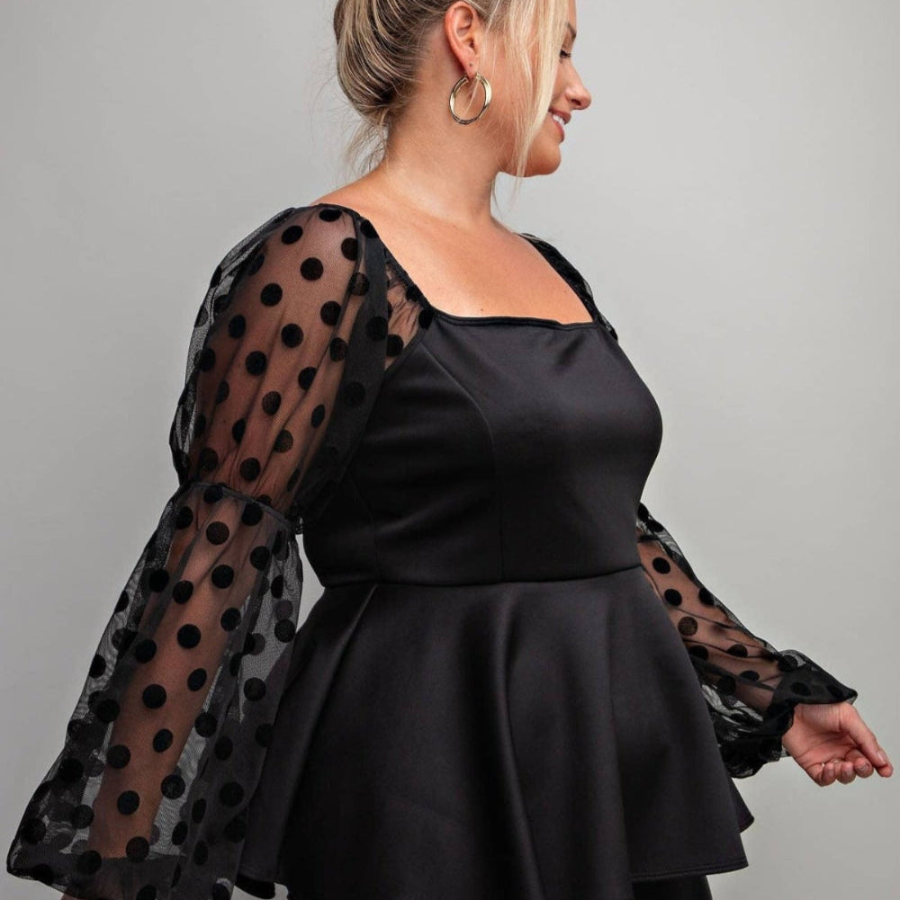 a woman wearing a black top with polka dots