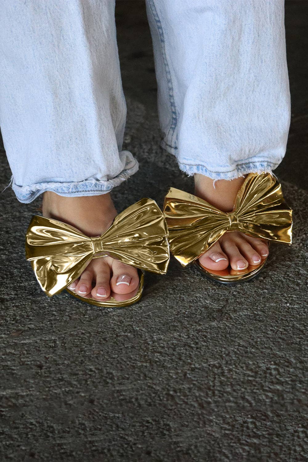 a person wearing gold sandals with a bow on them