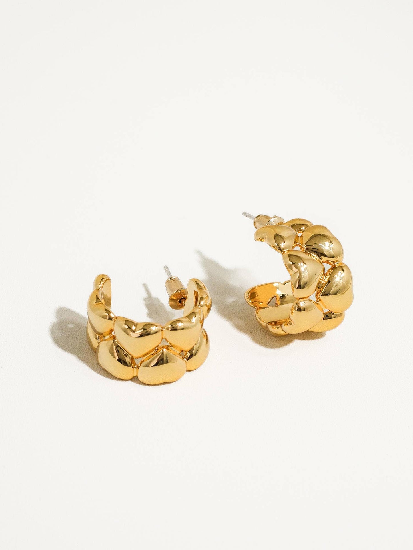 a pair of gold earrings on a white background