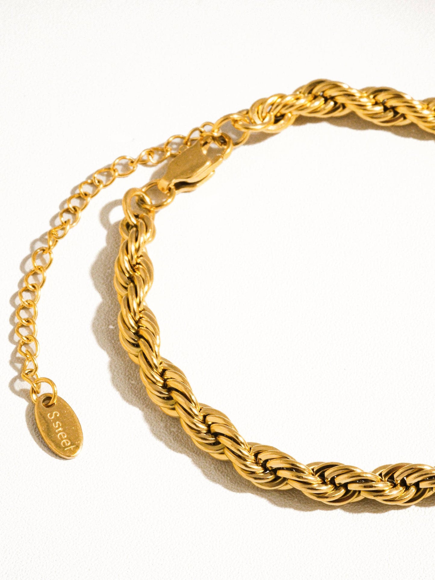 a close up of a gold bracelet on a white surface