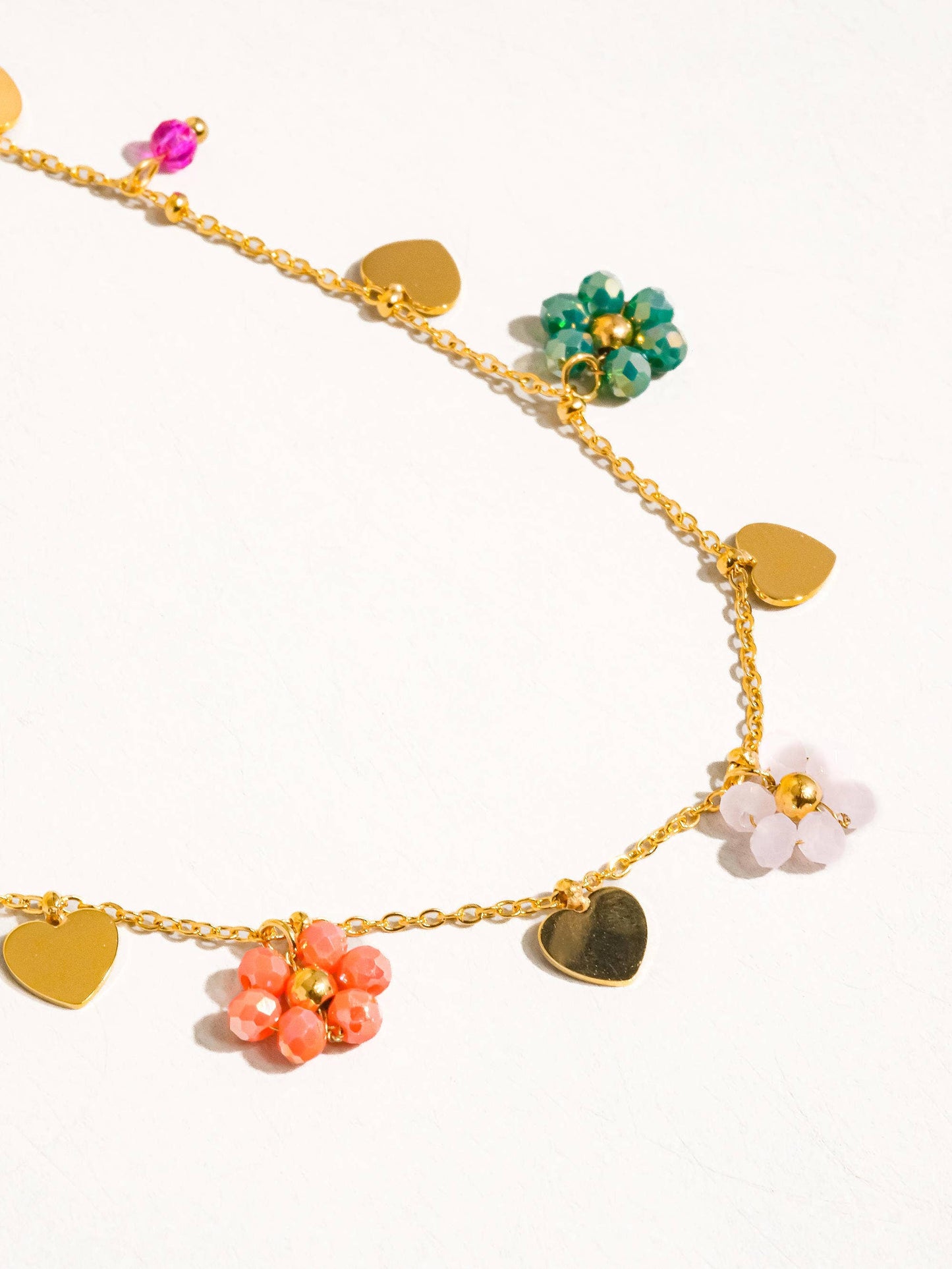 a gold chain bracelet with hearts and flowers