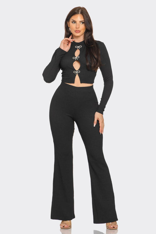 a woman wearing a black crop top and wide legged pants