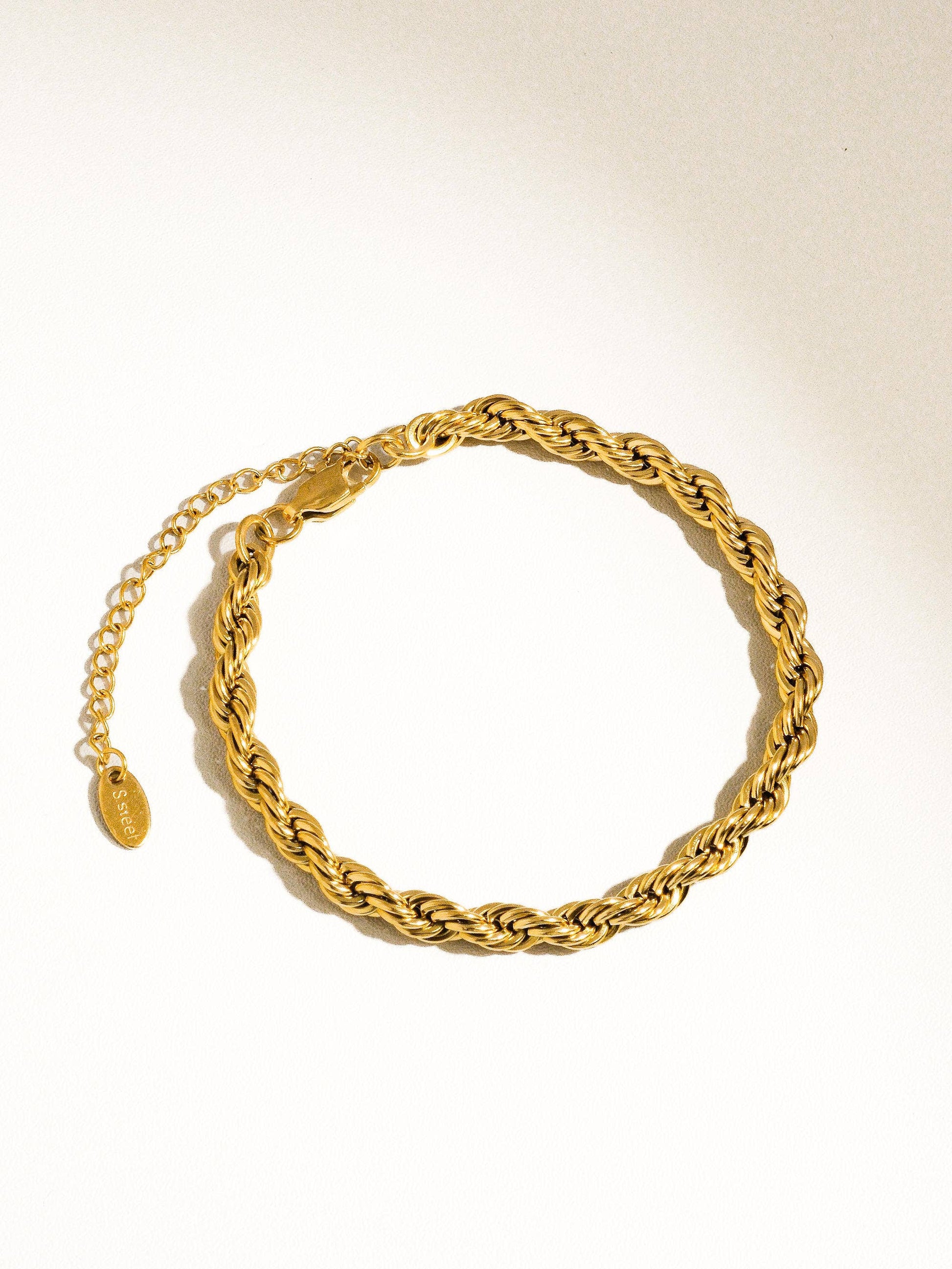 a gold chain bracelet on a white background