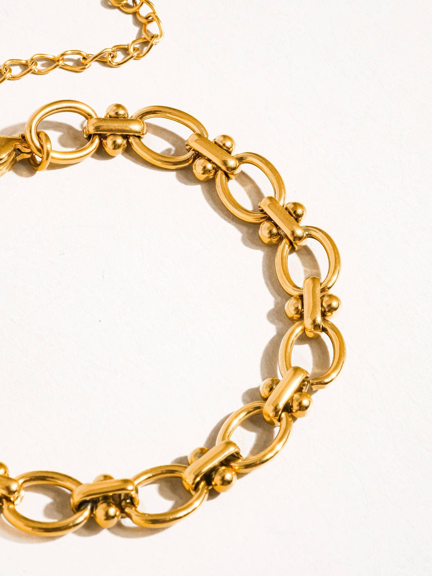 a close up of a gold bracelet on a white surface