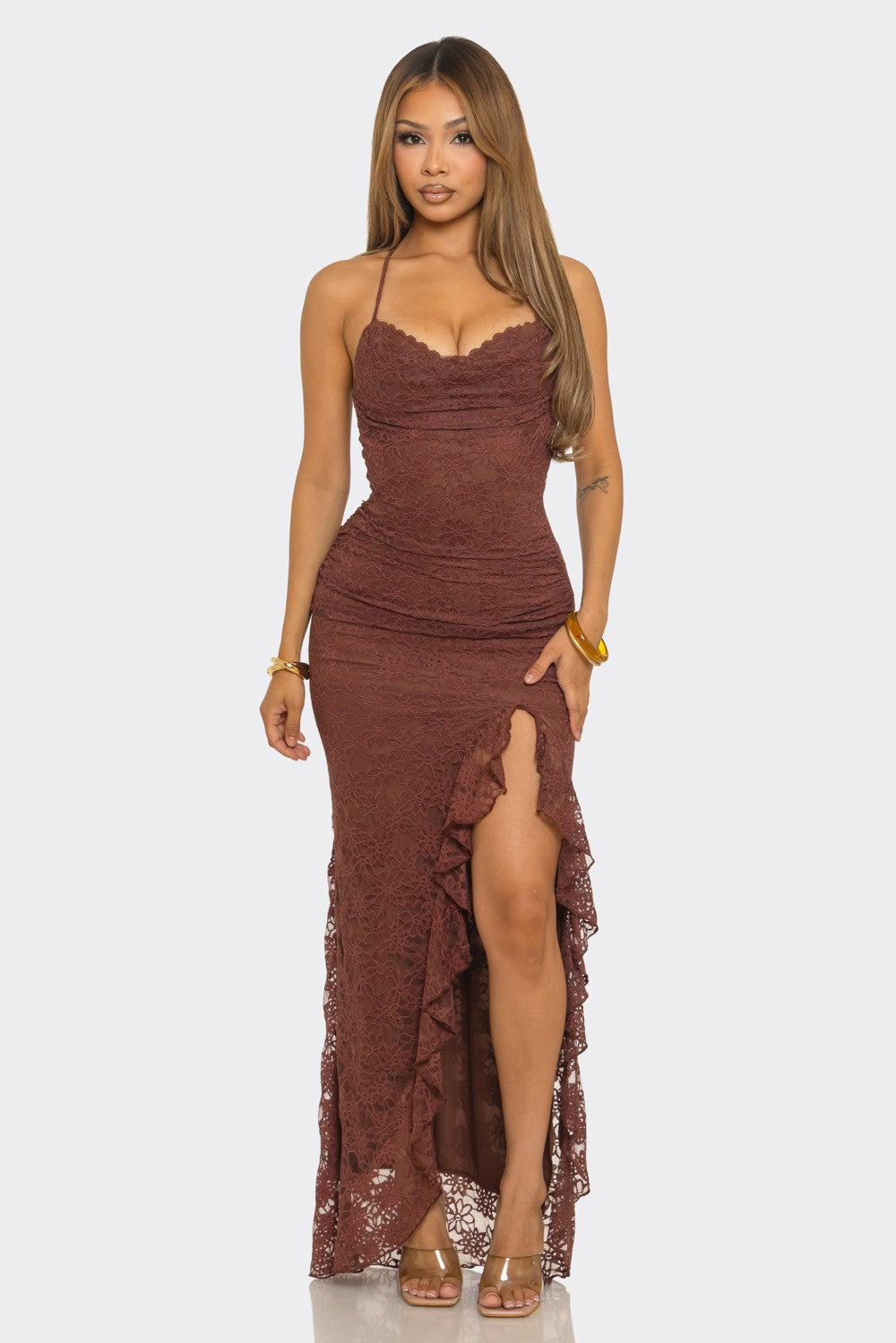 Brown lace maxi dress with spaghetti straps, ruched fitted silhouette, ruffle-trimmed thigh-high slit, and floor-length hem.