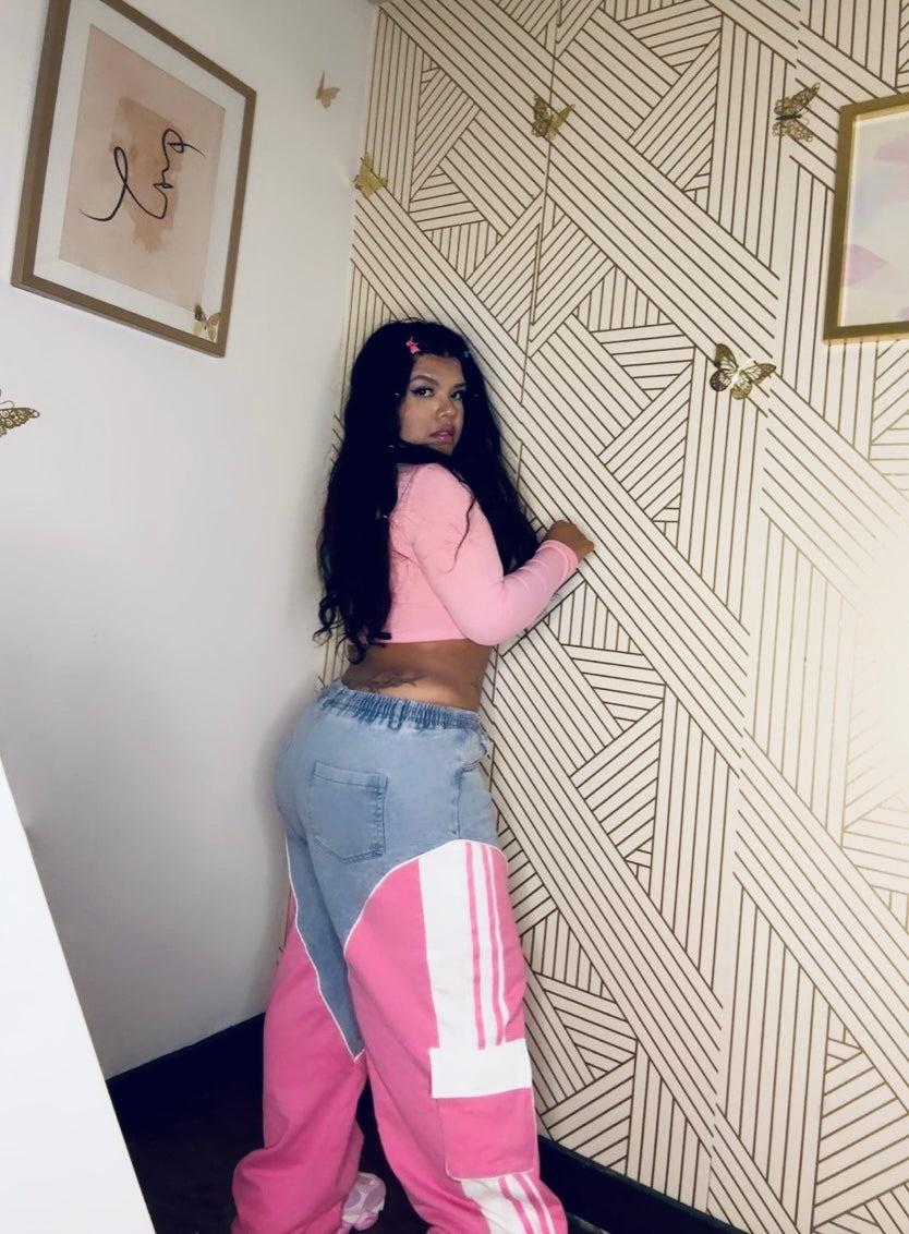 a woman standing next to a wall wearing pink and blue pants