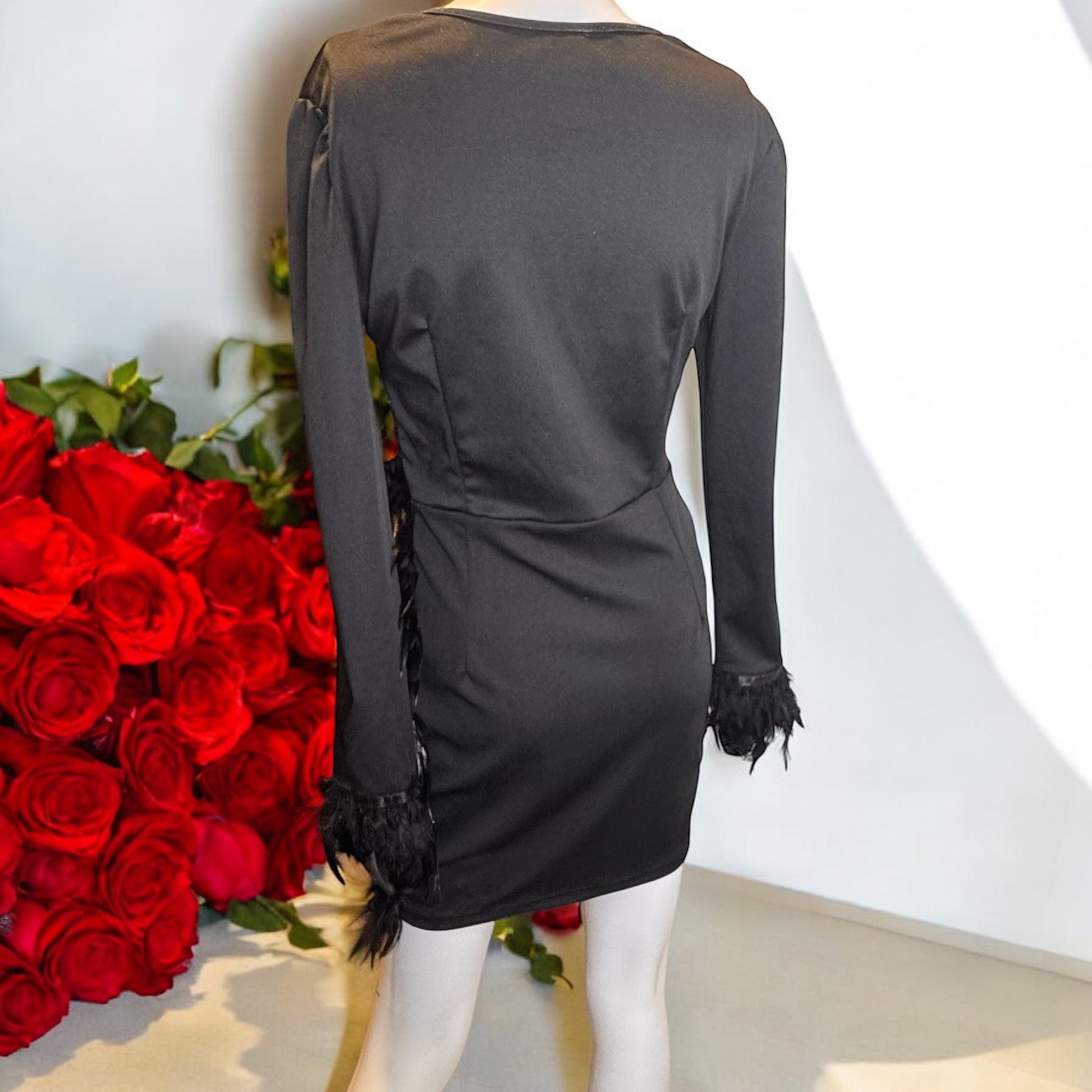 a mannequin dressed in a black dress next to a bouquet of red roses