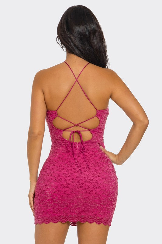 The back view of a woman wearing a stylish fuchsia mini dress with crisscross straps and a signature cutout design. Her hair flows down her back, adding elegance to the look.