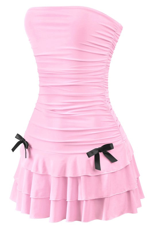 Stylish strapless babydoll dress in pink, featuring a ruched silhouette and elegant black bows, ideal for both casual and formal outings.