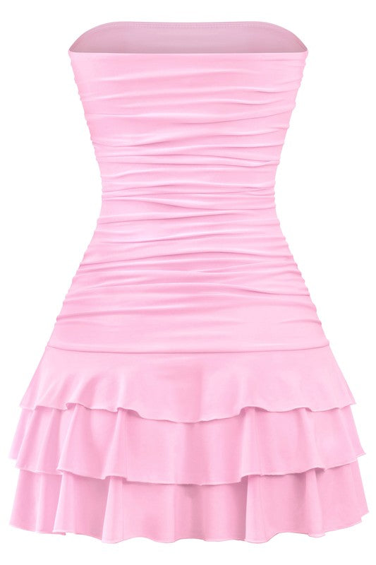 Charming pink strapless mini dress with a ruched look and layered skirt, enhanced by black bow accents, perfect for making a fashion statement.