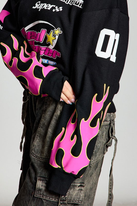 Model posing in a black sweatshirt with pink flame graphics on the sleeves, displaying 'Speed Chaser 01'. The casual look is complemented by loose-fitting gray pants.