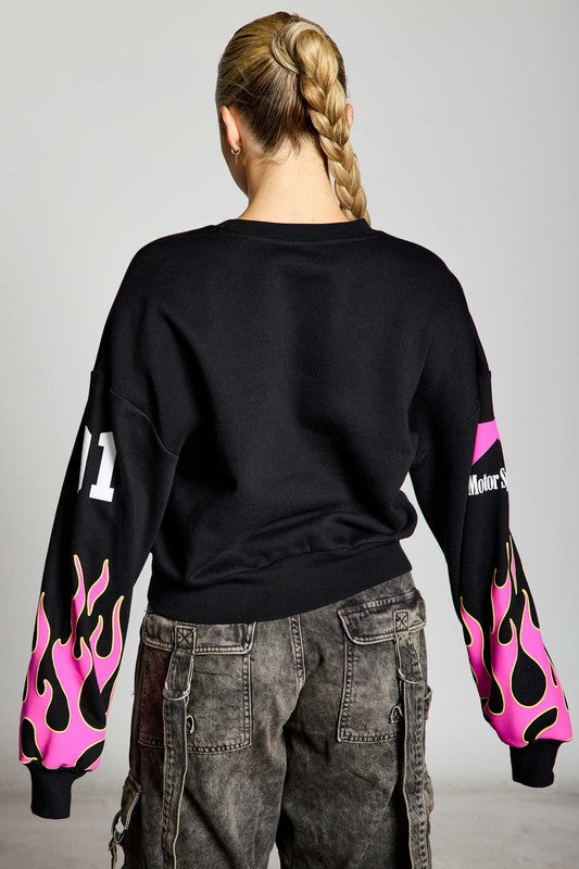 Back view of a model wearing a black sweatshirt with pink flame sleeves and the number '11' printed on one sleeve, showcasing a sporty and fashionable style.