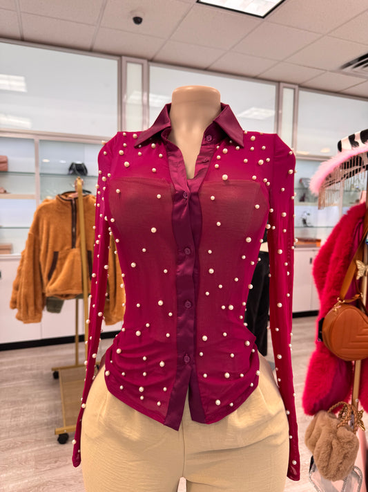 Elegant long sleeve mesh top in vibrant magenta adorned with pearl details, featured on a mannequin in a chic retail setting.