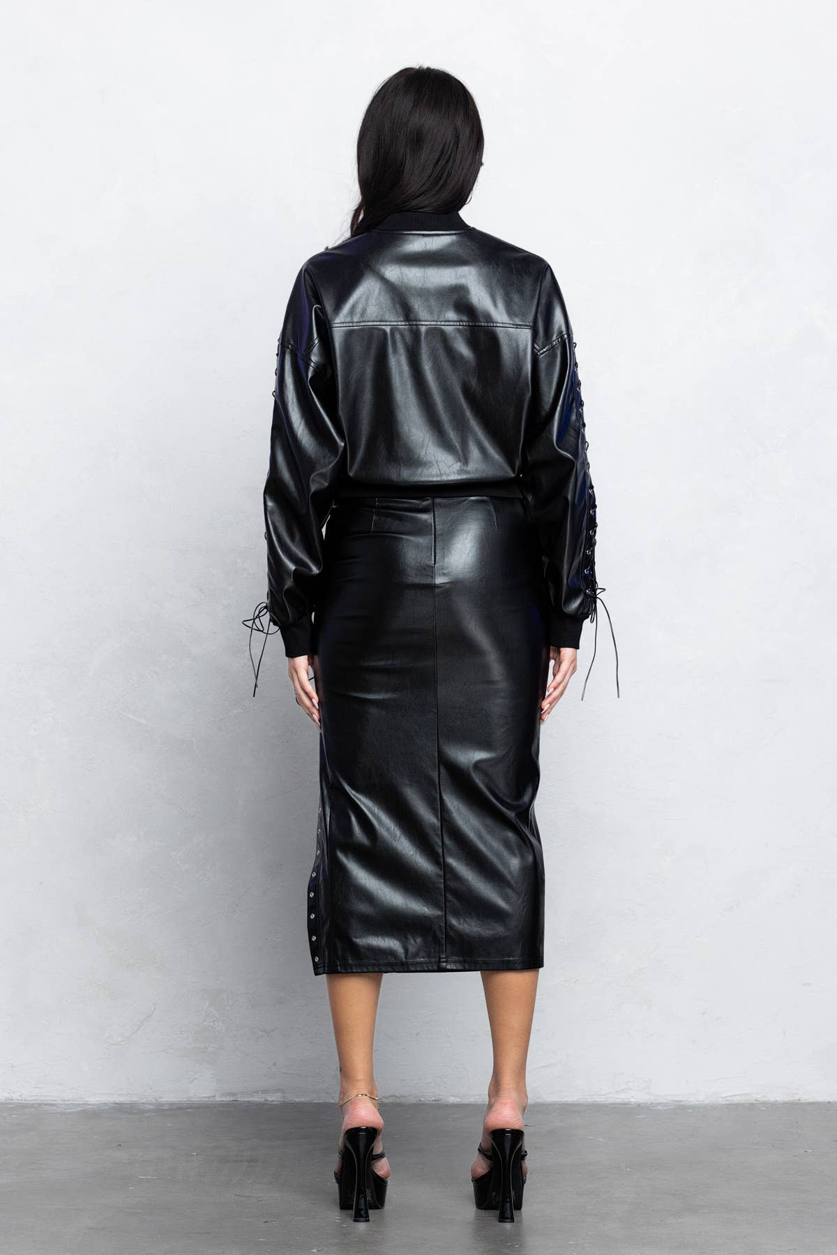 a woman wearing a black leather jacket and skirt