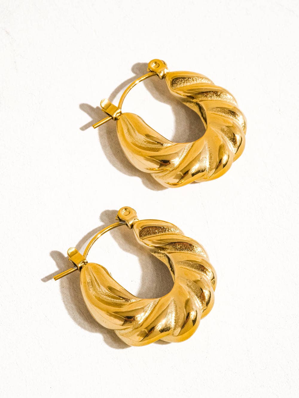 a pair of gold hoop earrings on a white background