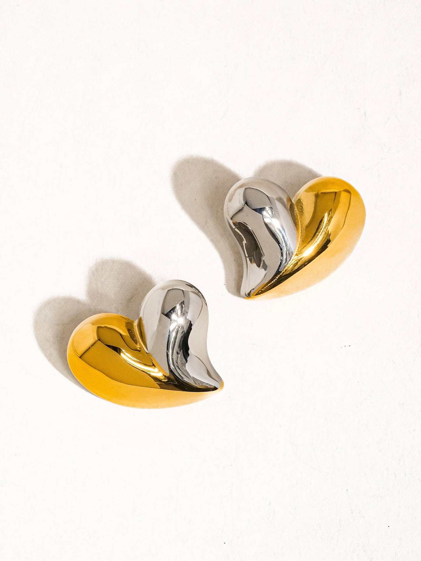 a pair of gold and silver earrings on a white background