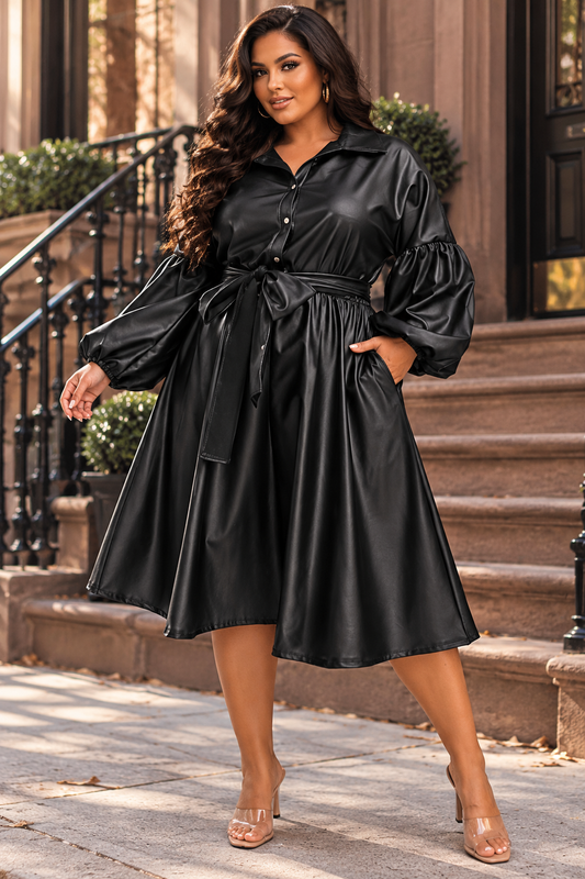 Plus-size model wearing the Victoria black faux leather midi dress featuring puff sleeves, button-front detailing, a belted waist, and a flared skirt.