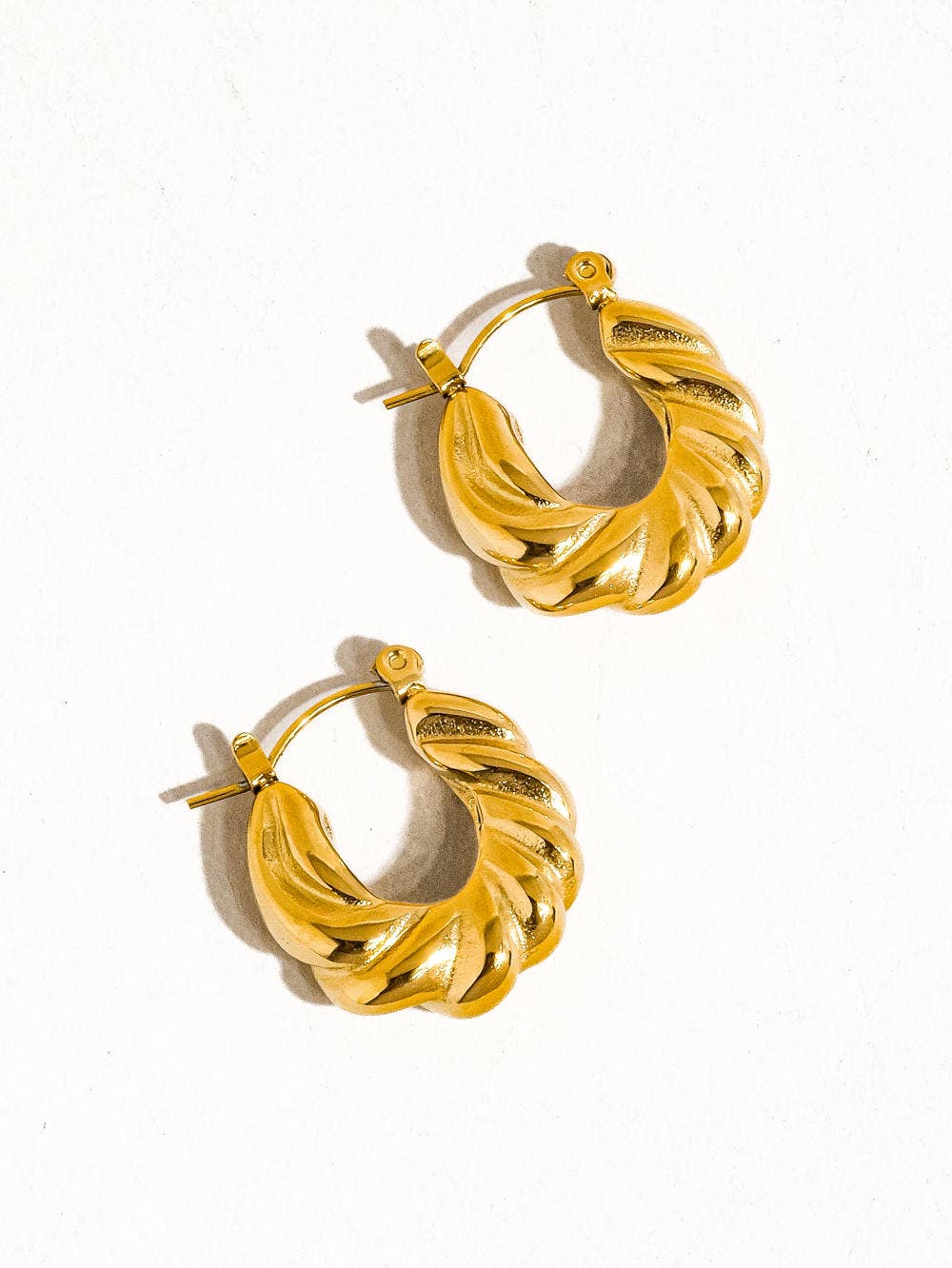 a pair of gold hoop earrings on a white background