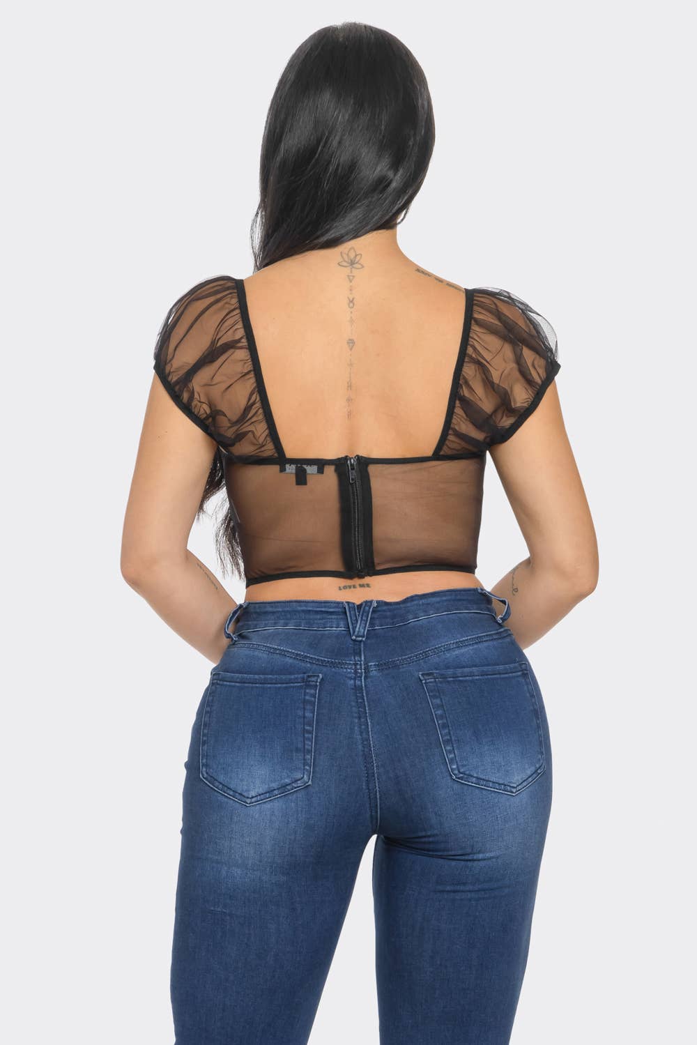 the back of a woman wearing jeans and a sheer top