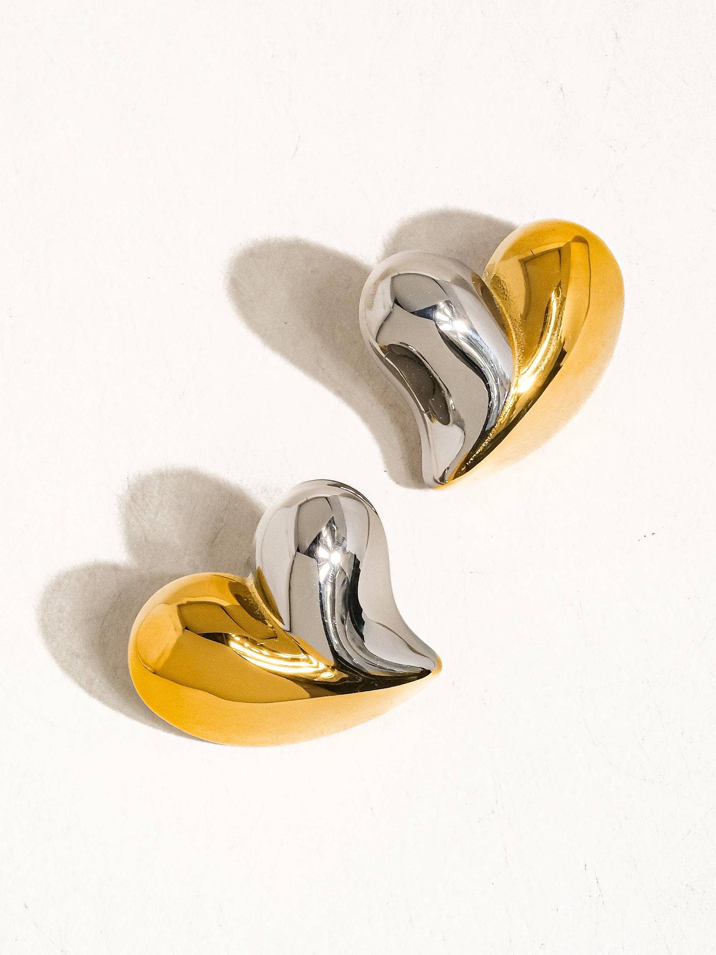 a pair of gold and silver earrings on a white surface