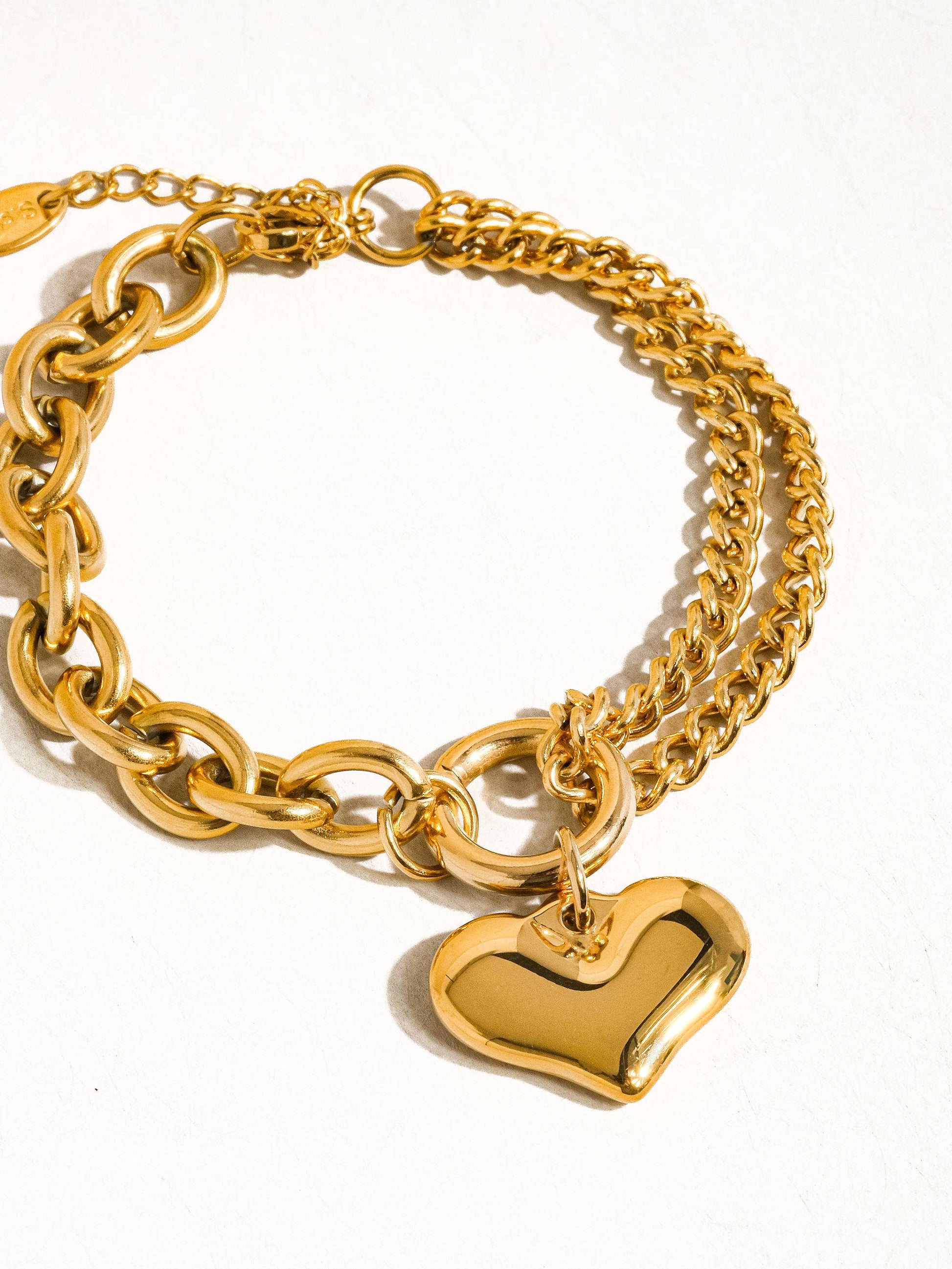 a gold chain bracelet with a heart charm